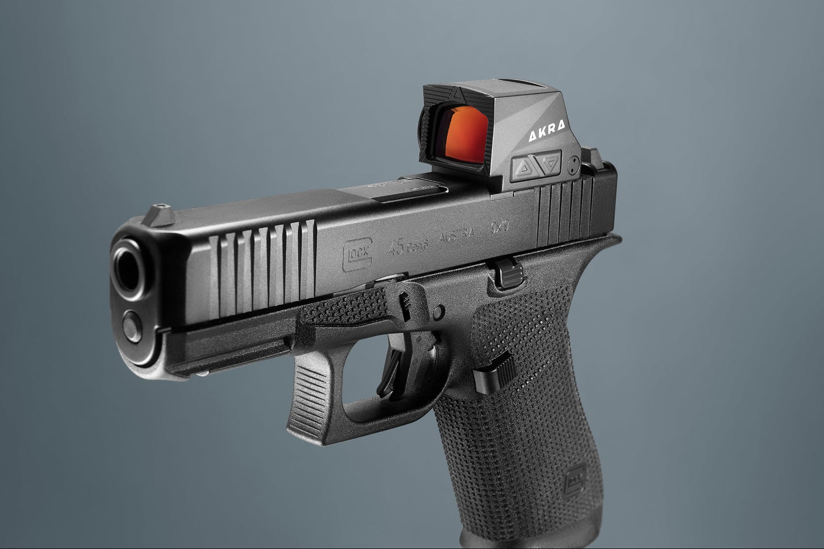 A black semi-automatic pistol with a red dot sight mounted on top, shown against a solid gray background.